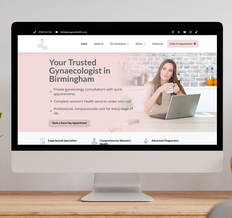 A desktop monitor displaying the Your Gynae Health website, featuring a woman at a laptop and information about private gynaecology consultations in Birmingham.
