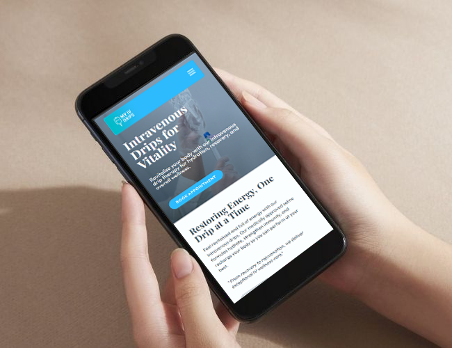 A person holding a smartphone showing the "My IV Drips" website homepage, featuring a call to action for booking intravenous therapy appointments.