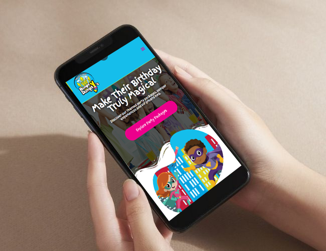 Hands holding a smartphone displaying a colorful children’s birthday website on the screen.