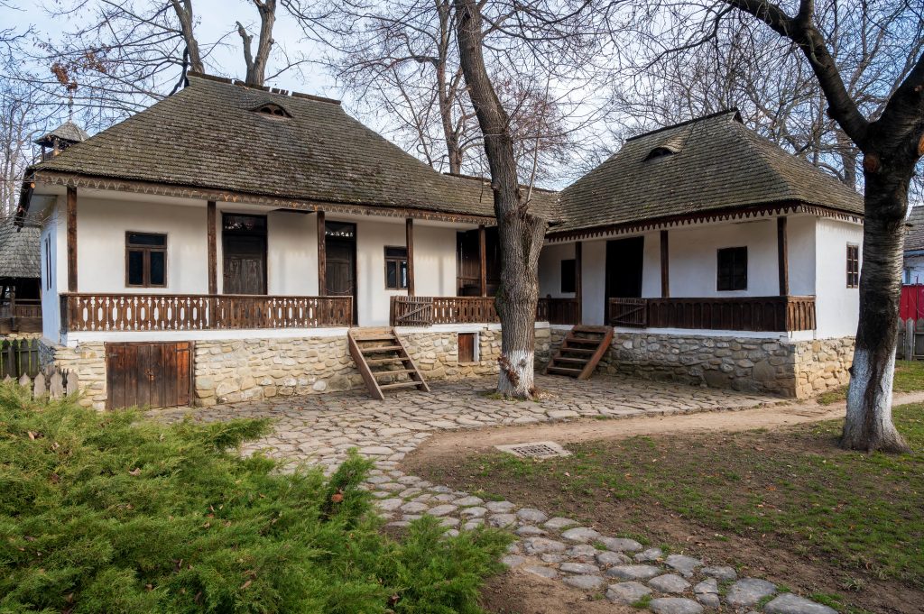 Traditional rural houses with white walls, wooden porches, and shingled roofs surrounded by leafless trees.