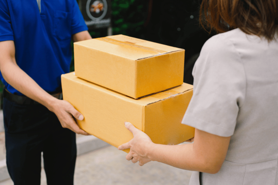 Person handing two delivery boxes to another person.