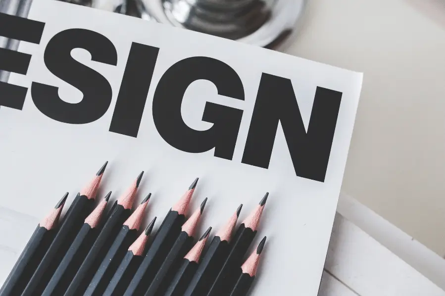 Pencils arranged next to the word ‘DESIGN’ on paper.