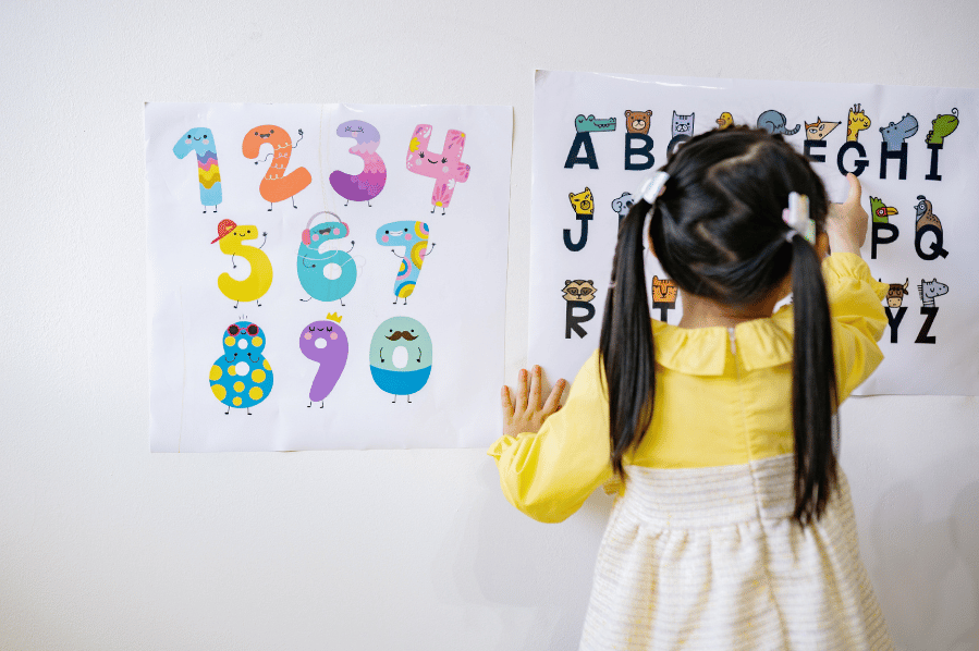 Child pointing at an alphabet chart on a wall.
