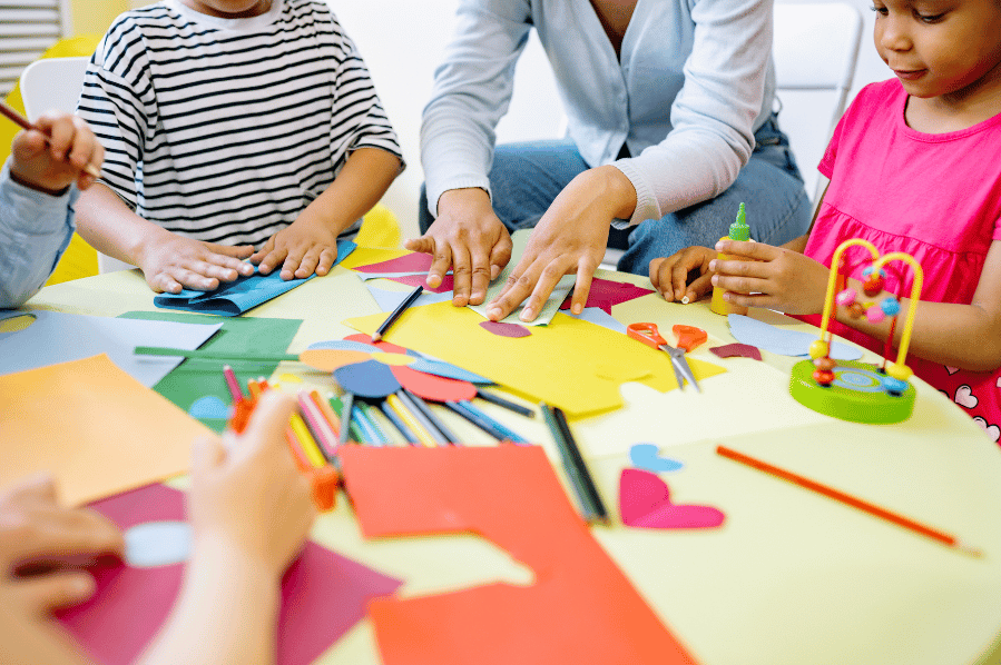 Children and an adult doing arts and crafts together at a table.
