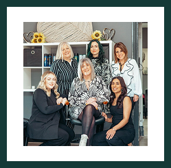 A smiling team of women from Region Accountancy posing together in a relaxed office setting.