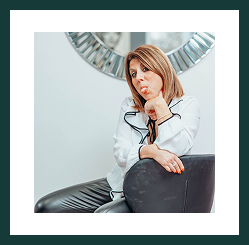 A Region Accountancy team member sitting on a chair, smiling thoughtfully in the office.