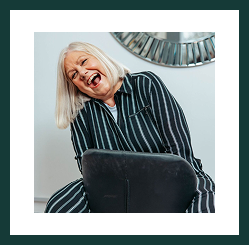 A smiling woman from the Region Accountancy team leaning playfully over a chair in the office.