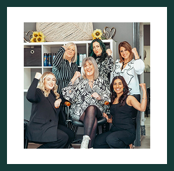 A smiling team of women from Region Accountancy posing together in a relaxed office setting.